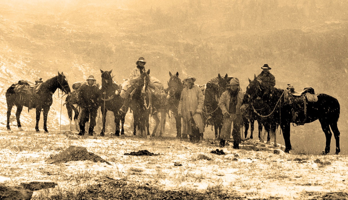 Riders and loaded pack horses in falling snow at the end of a bighorn sheep hunt in the Gros Ventre Range, 1998